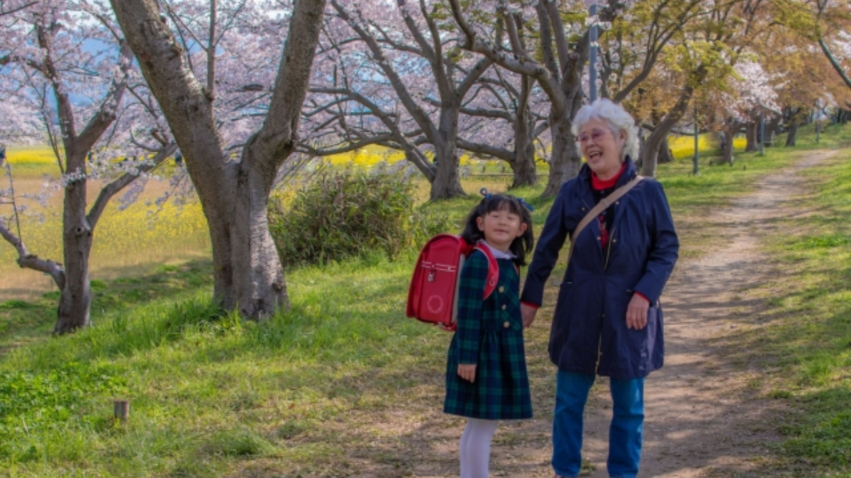 桜の木の下を一緒に歩く祖母と孫