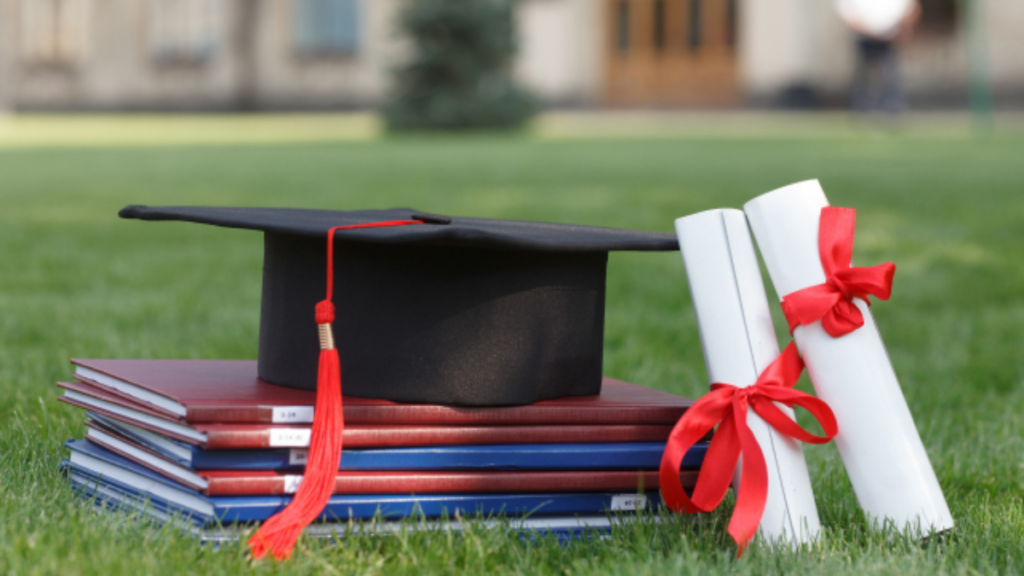 芝生の上の教科書と卒業証書と帽子